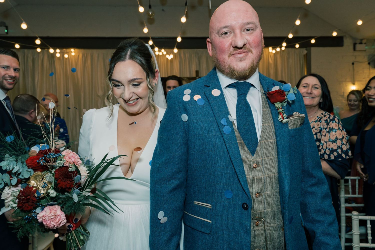 Joyful wedding celebration with confetti shower in indoor venue.