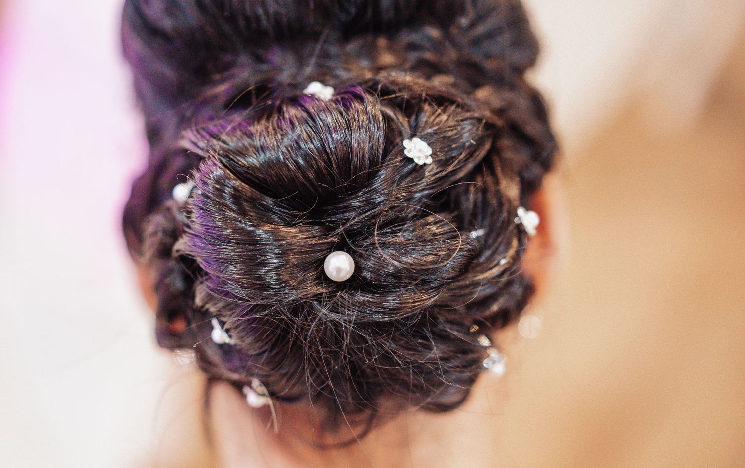 Elegant bridal updo hairstyle with delicate pearl pins and intricate styling.