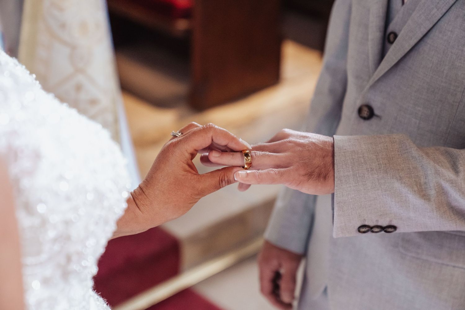Close-up shot of wedding rings being exchanged during ceremony.