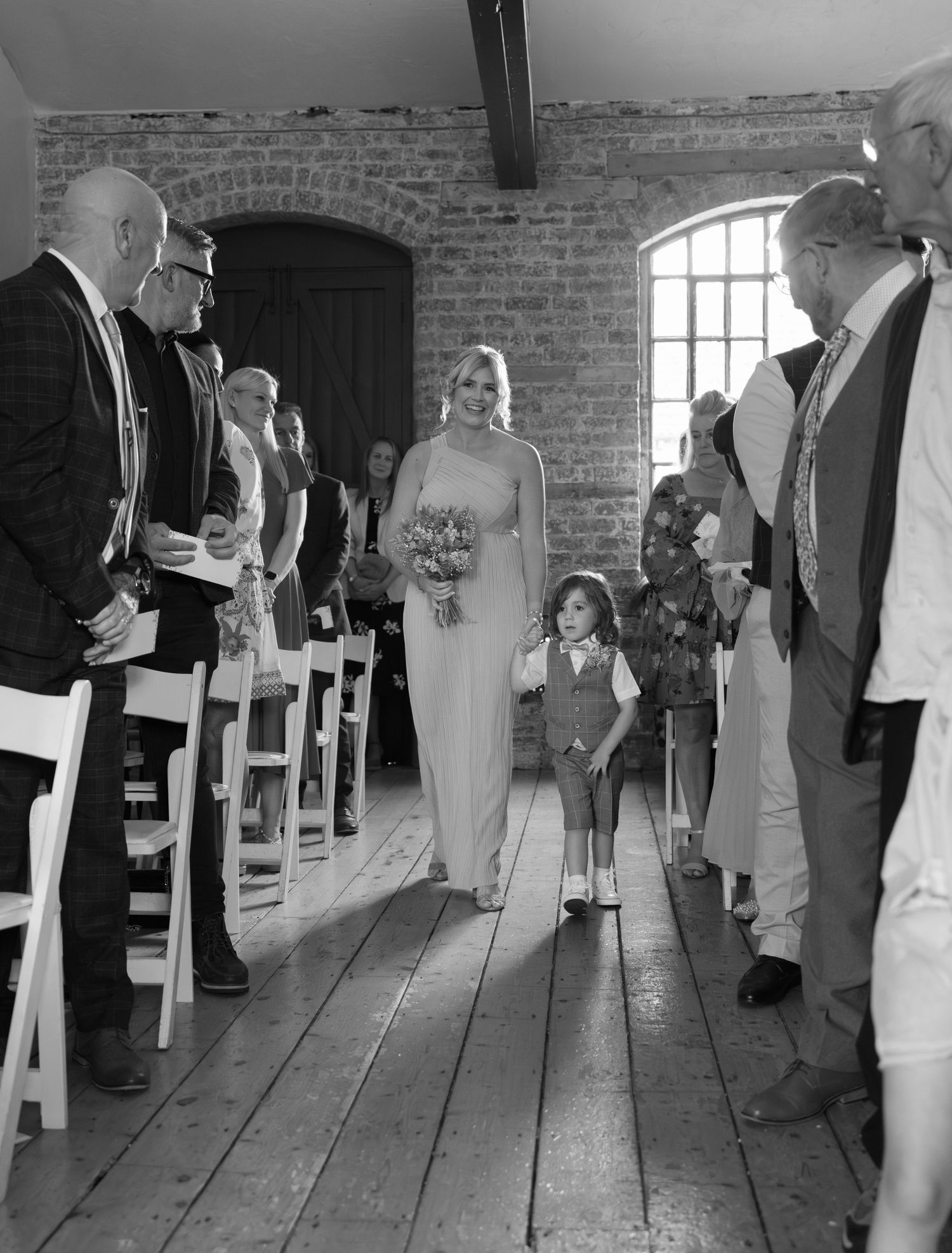 Wedding guests mingling in a historic brick venue with wooden floors.