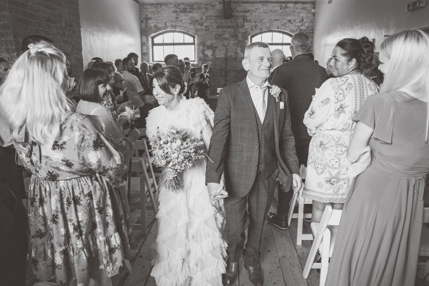 Wedding guests gather in a rustic brick-walled venue for the celebration.