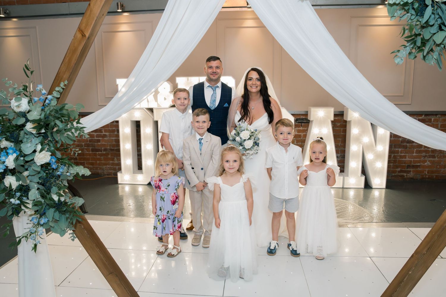 Wedding ceremony setup with white draping and floral decorations in an elegant indoor venue.