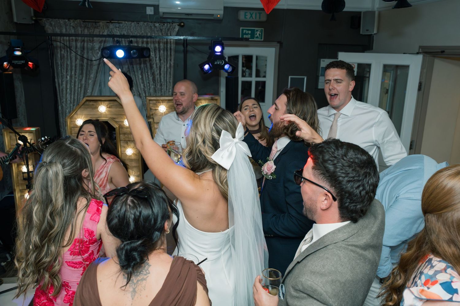 Lively dance party scene with colorful lights and guests dancing.