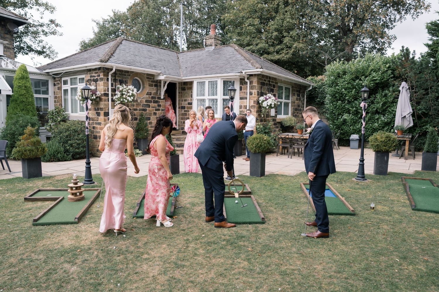 Wedding guests playing lawn games at an outdoor garden reception on a sunny day.