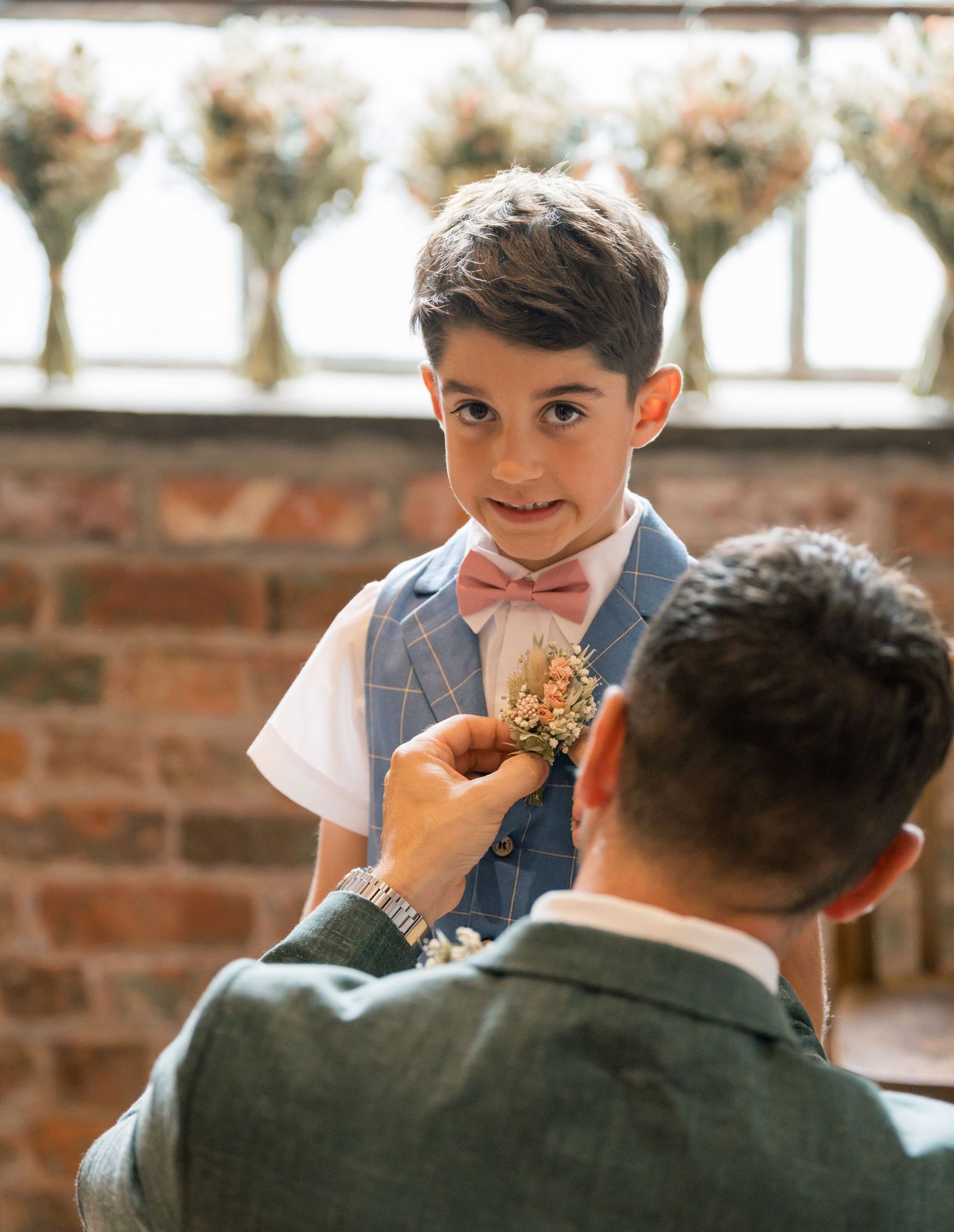 A boutonniere being pinned onto formal attire at a wedding.