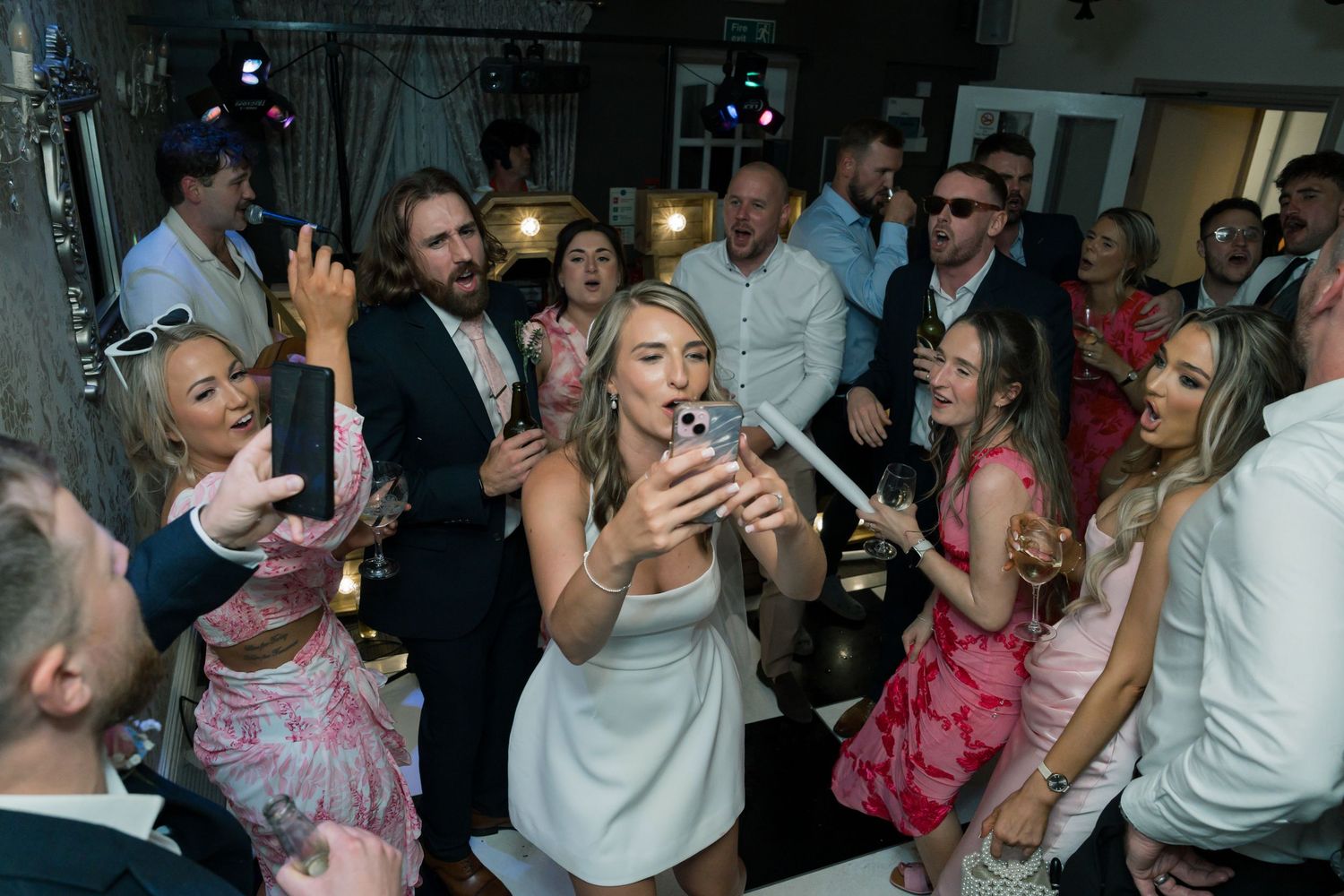 A group of people at a party blowing bubbles together in an indoor setting.
