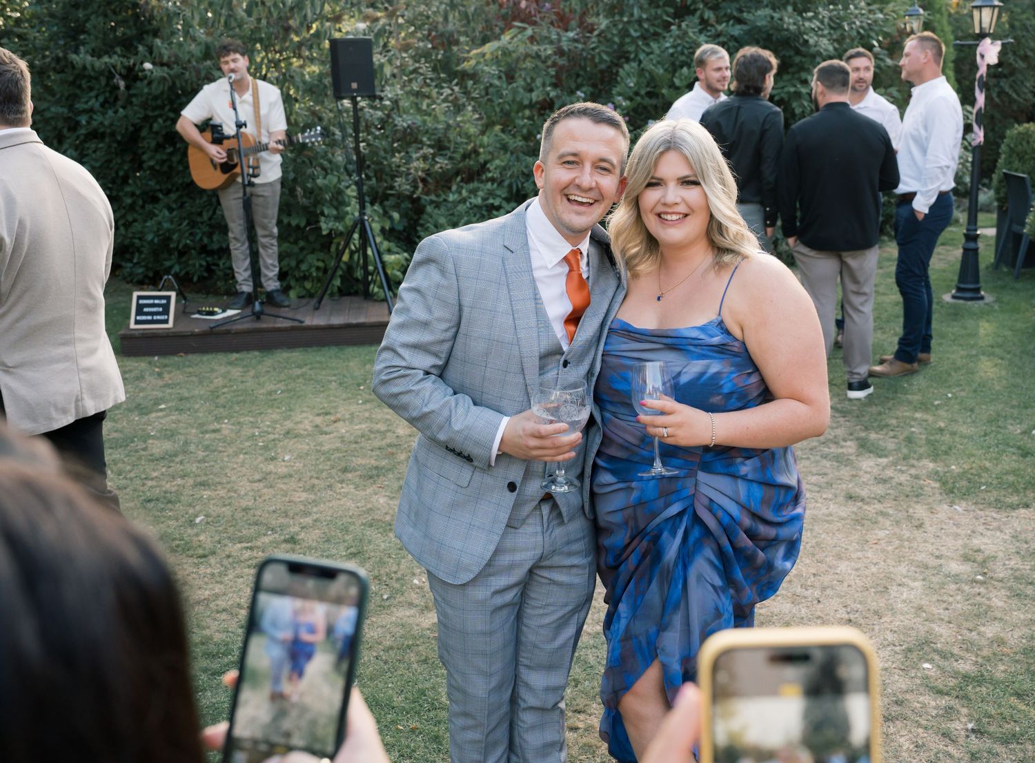 Wedding guests mingle and socialize at outdoor garden reception.