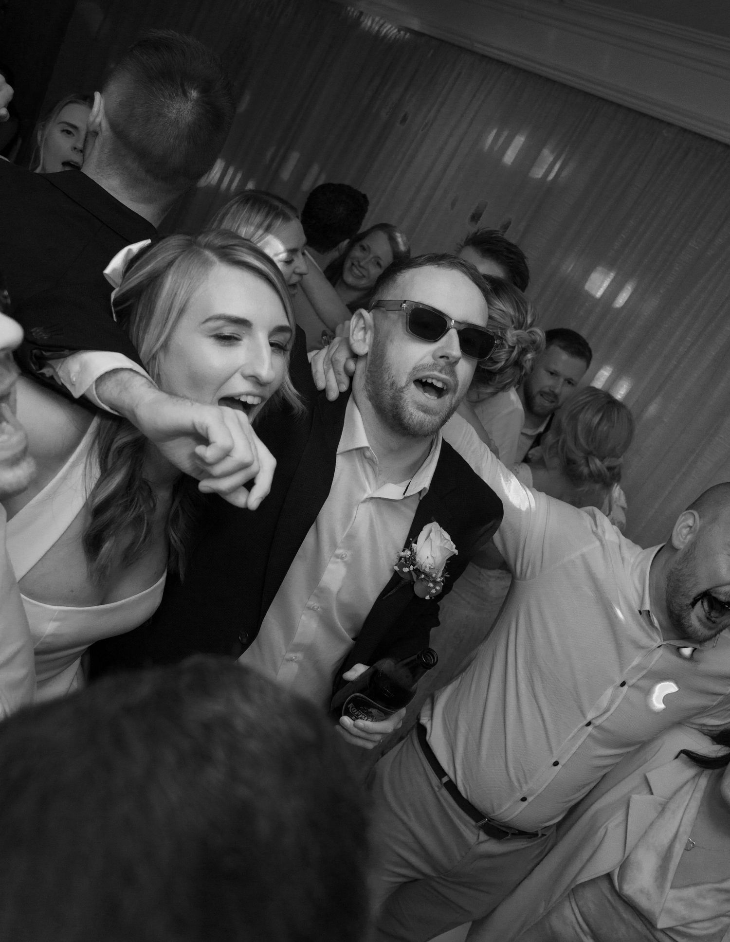 Black and white photo of wedding reception dance party with energetic guests.