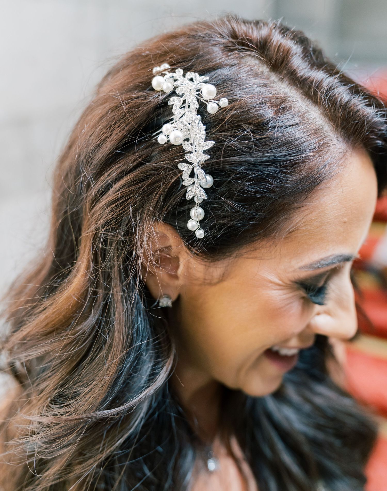 Delicate crystal floral hair accessory adorning dark wavy hair in bridal style.