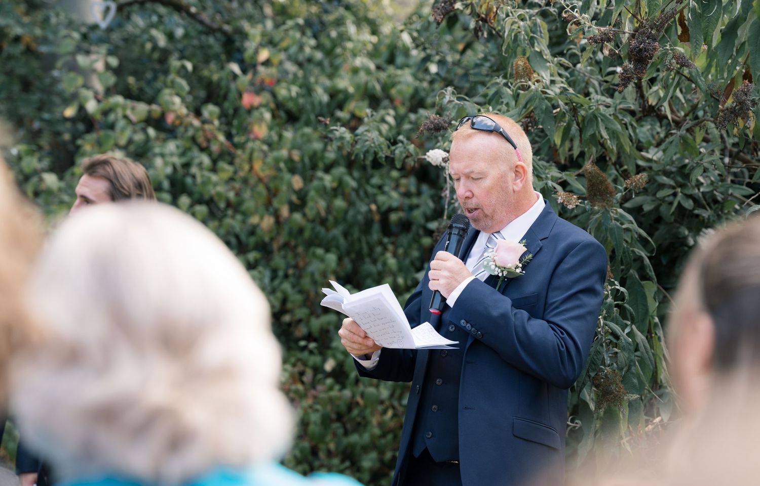 Wedding party gathered outdoors for candid group photos among trees and greenery.