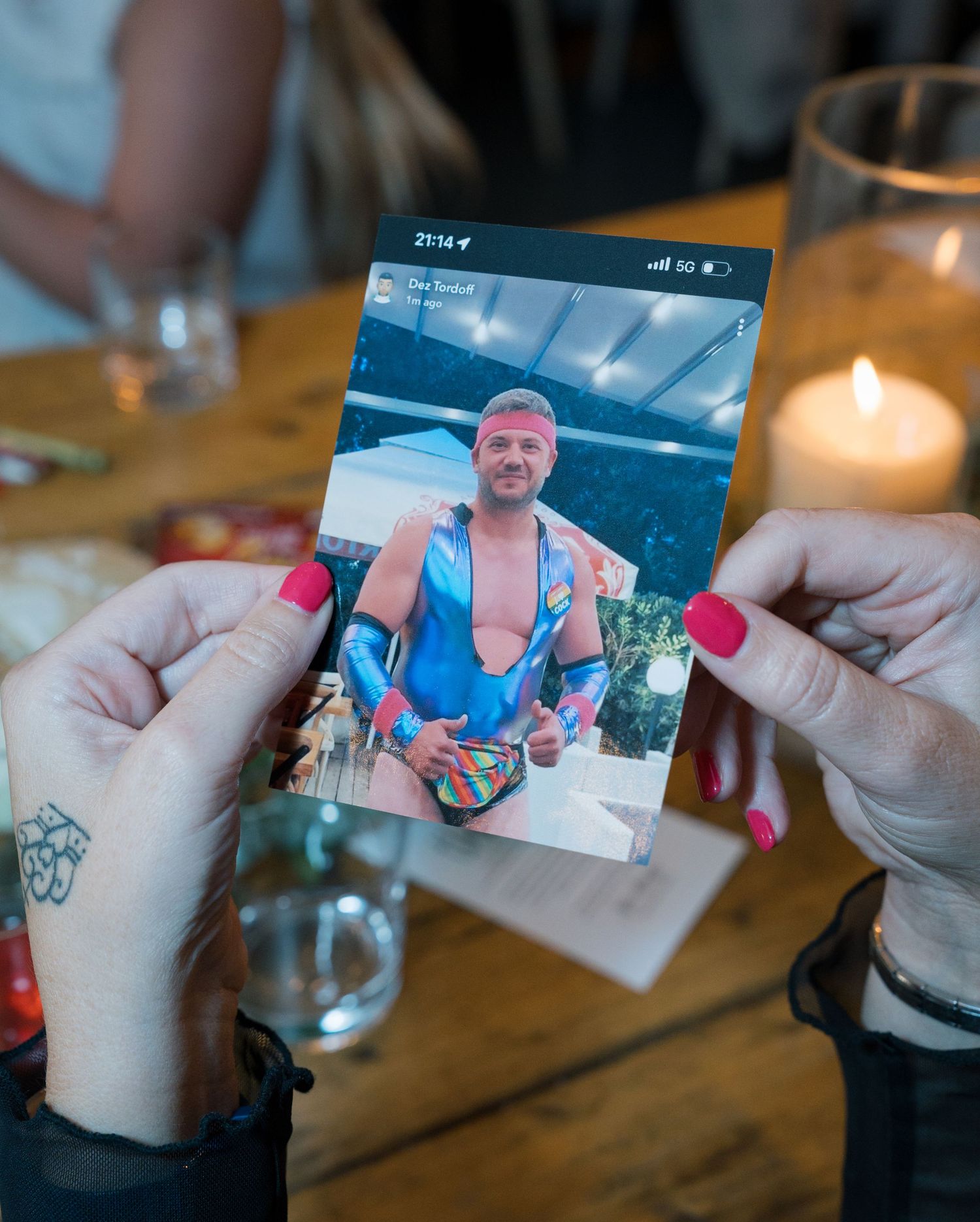 Hands holding and passing wedding photos across wooden table.