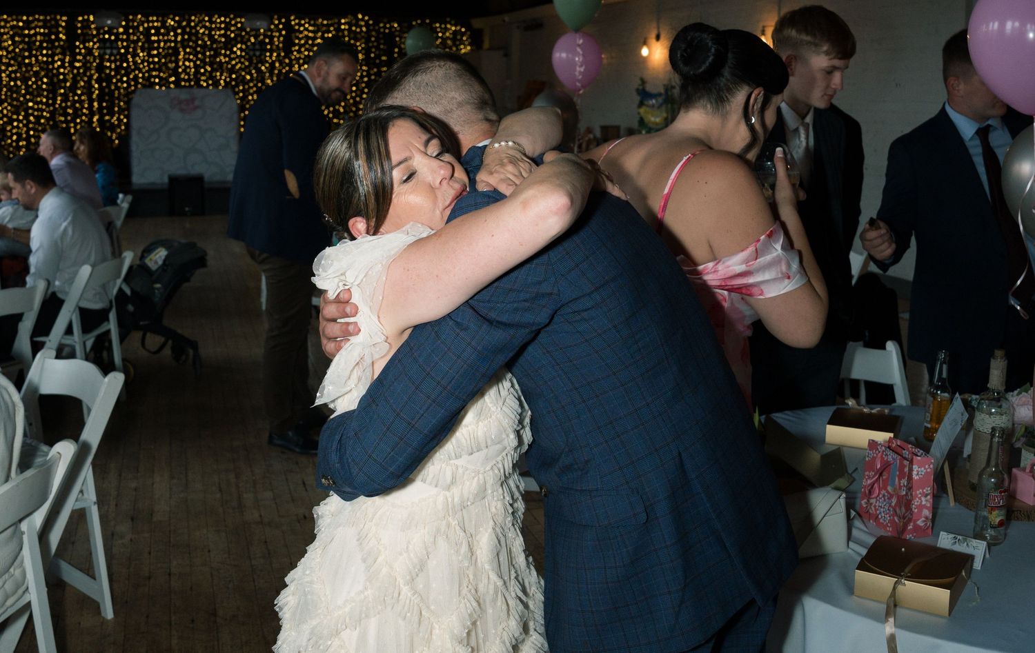 Wedding reception dance floor with string lights and purple balloons creating a festive atmosphere.