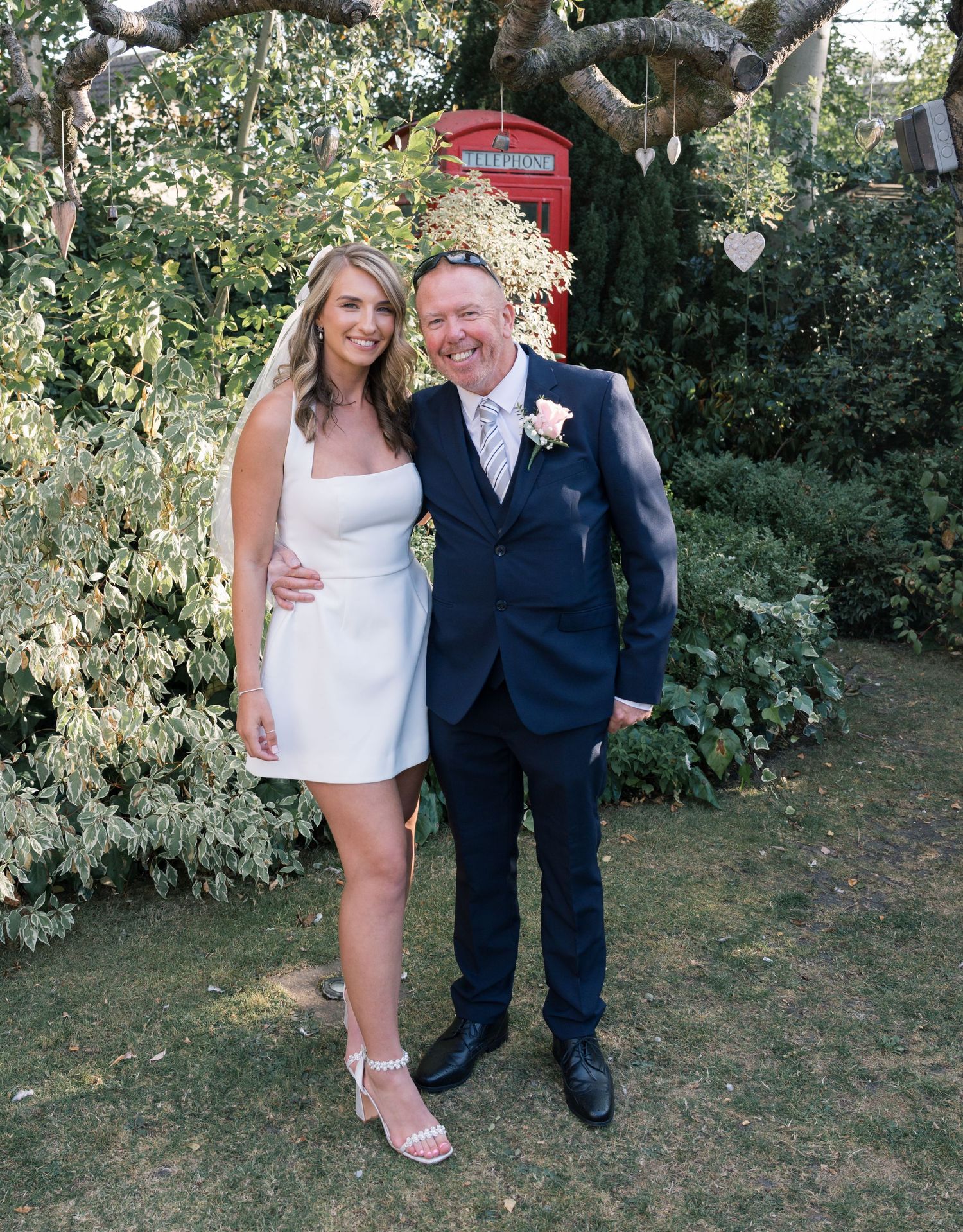 A couple poses together in formal attire under a tree during their wedding day.