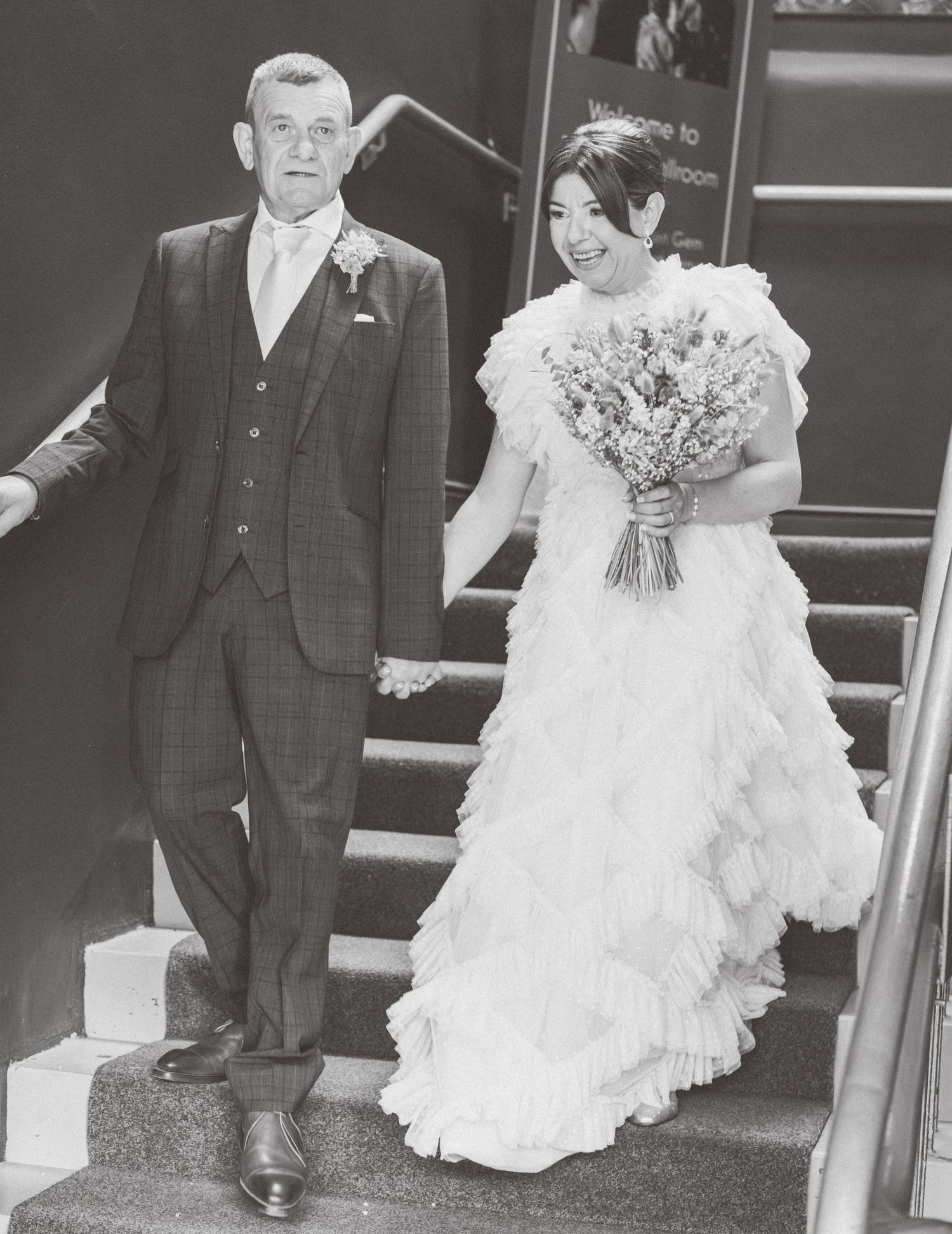 Black and white photos capture wedding party walking down stairs in formal attire.