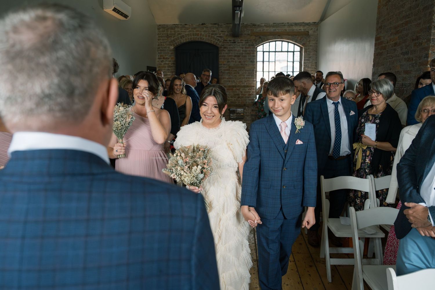 Wedding party celebrates in a rustic brick venue with guests dancing and mingling during the reception.