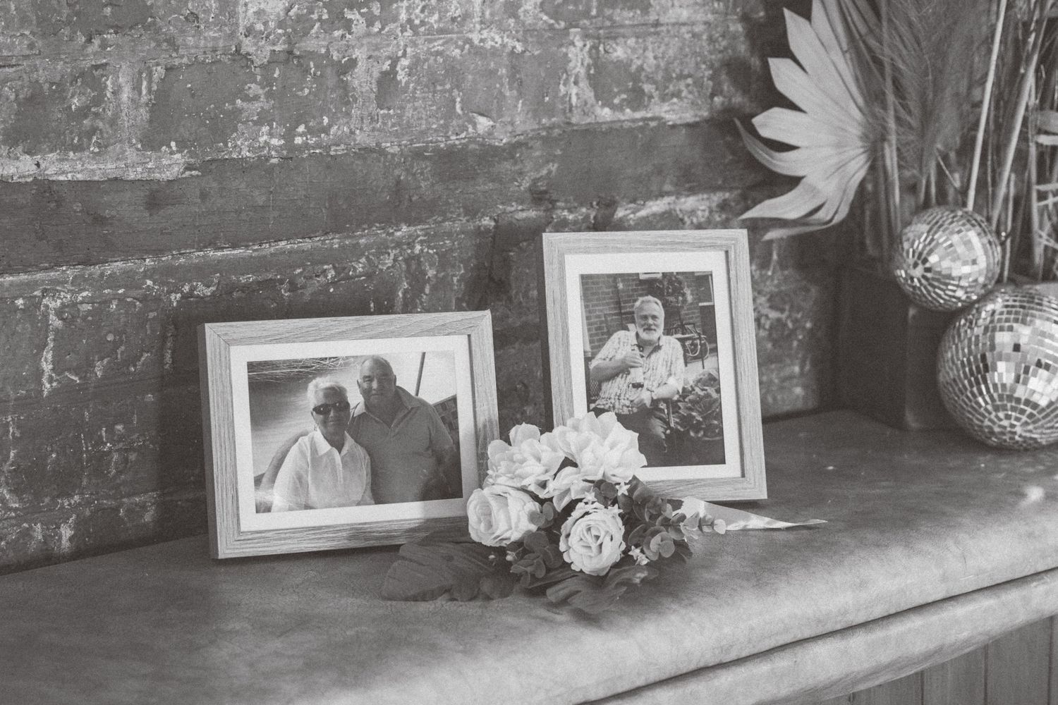 A collection of black and white photographs displayed on a rustic stone wall with decorative flowers.