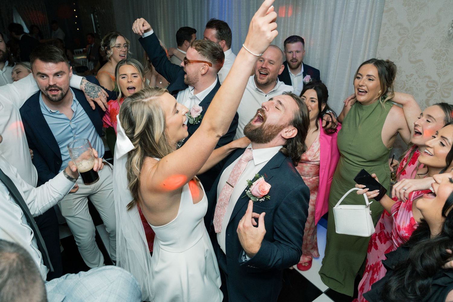 Lively group of wedding guests dancing and celebrating at reception.