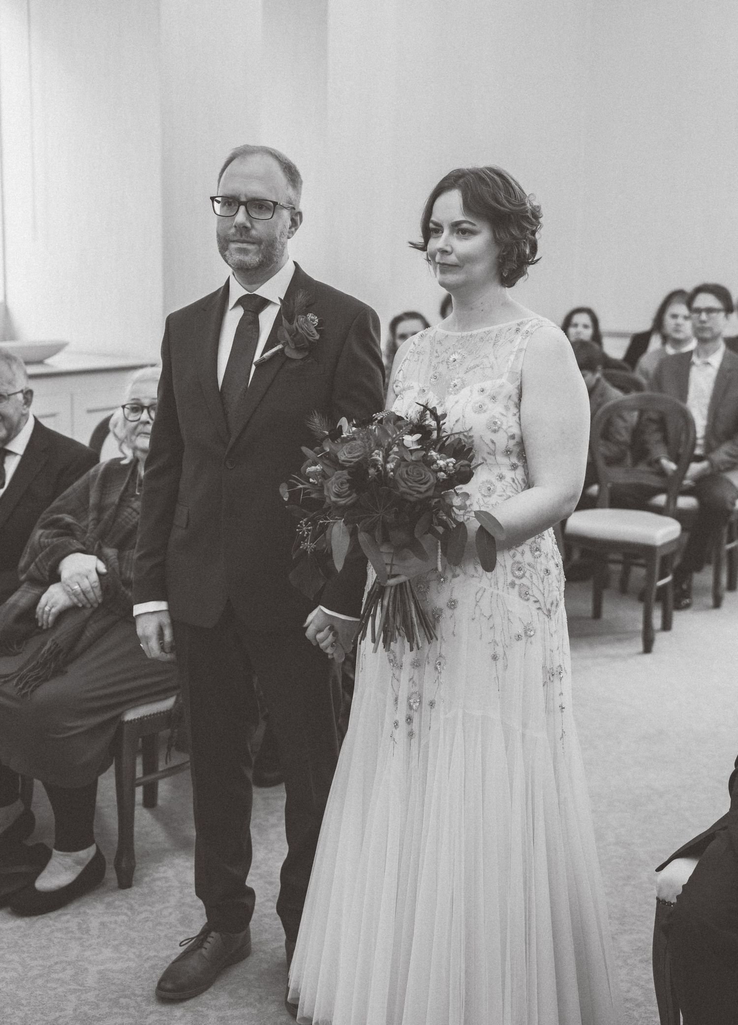 A black and white wedding ceremony photo showing a couple in formal attire during their special moment.