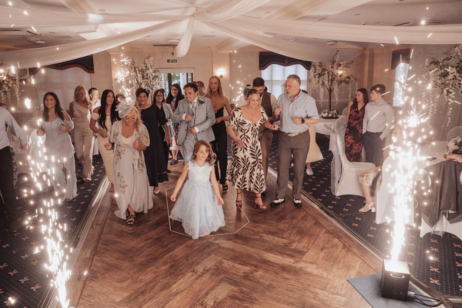 Wedding reception dance floor filled with guests and sparkler effects creating magical atmosphere.