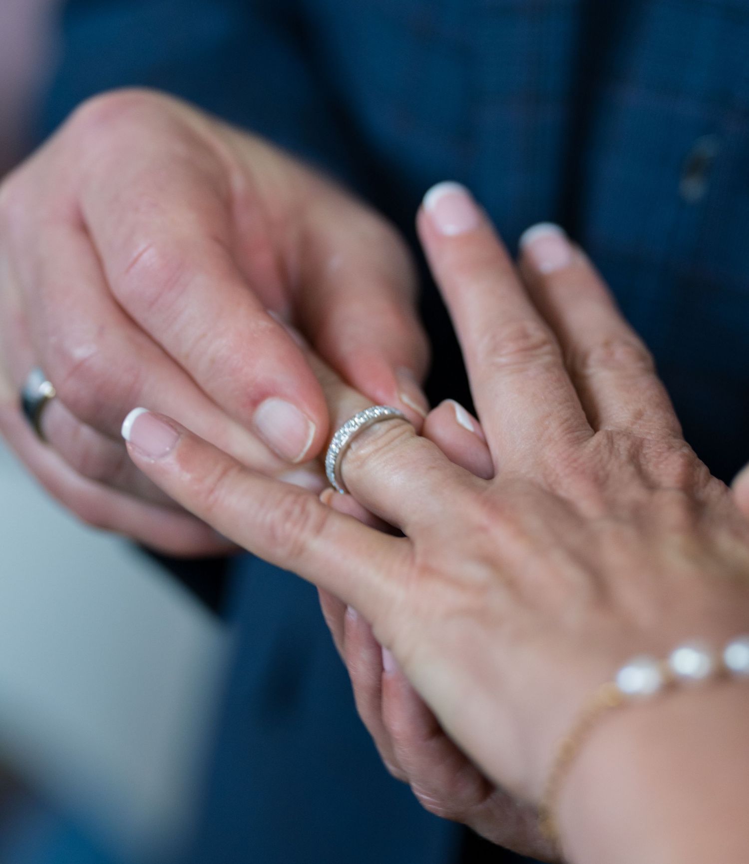 Close-up of hands exchanging wedding rings during ceremony.