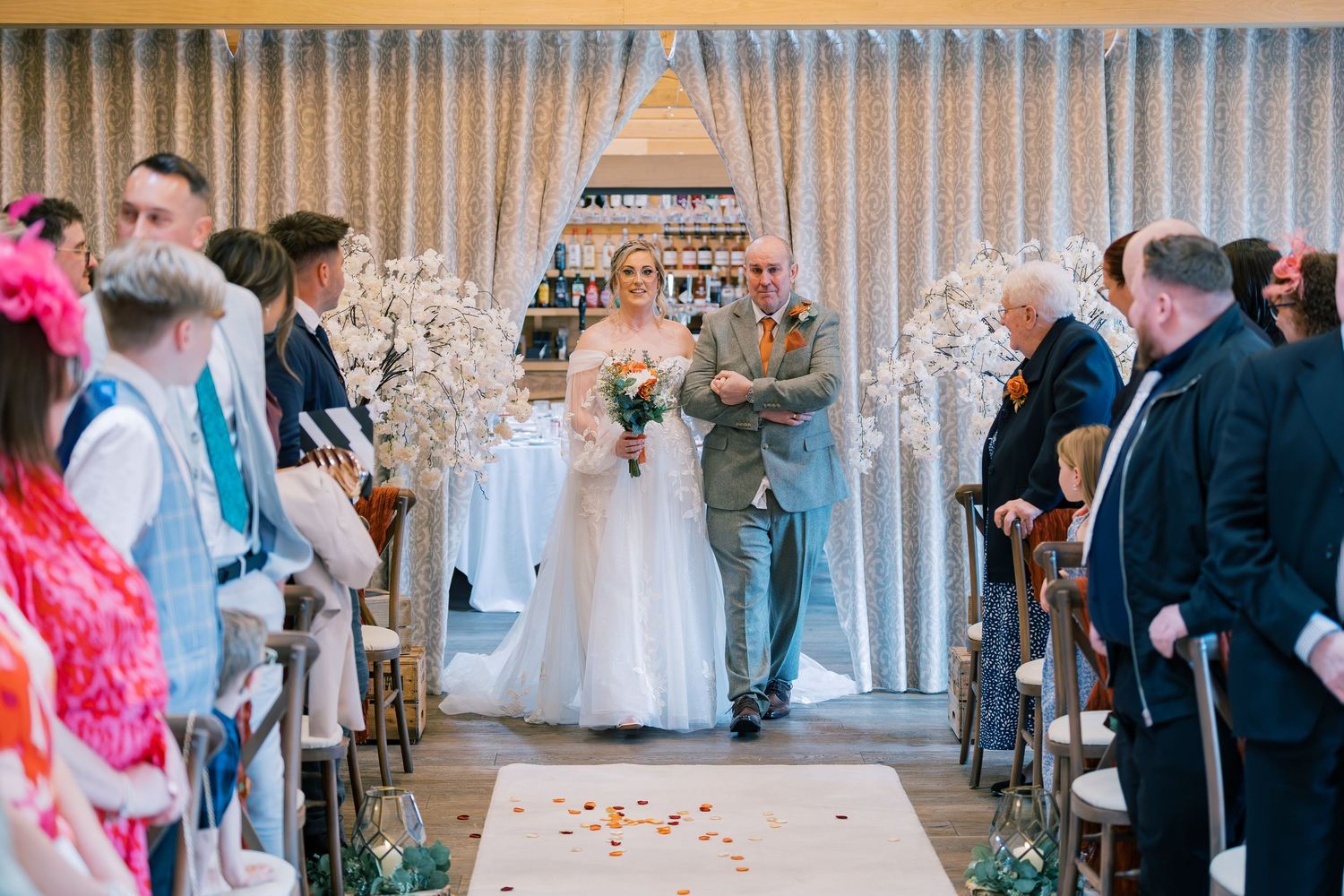 Wedding guests play a game of beer pong on a white table during an indoor reception celebration.