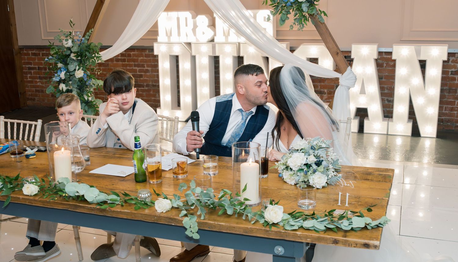 Wedding reception space with illuminated letter decor and rustic table settings.