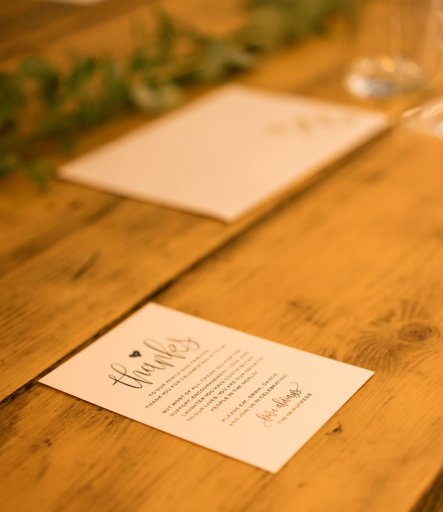 Wedding invitation cards arranged in a row on a rustic wooden surface with warm lighting.