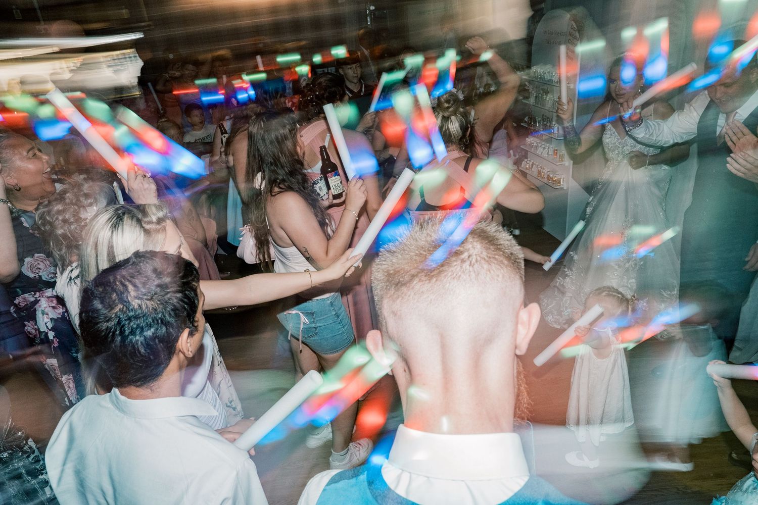 People dancing and having fun at a crowded nightclub with colorful lighting effects and motion blur.