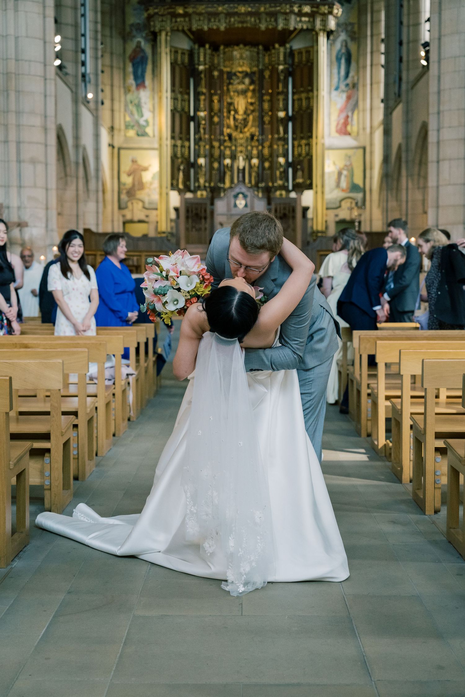 A sequence of photos showing a couple falling backwards during their wedding photoshoot in a grand church setting.