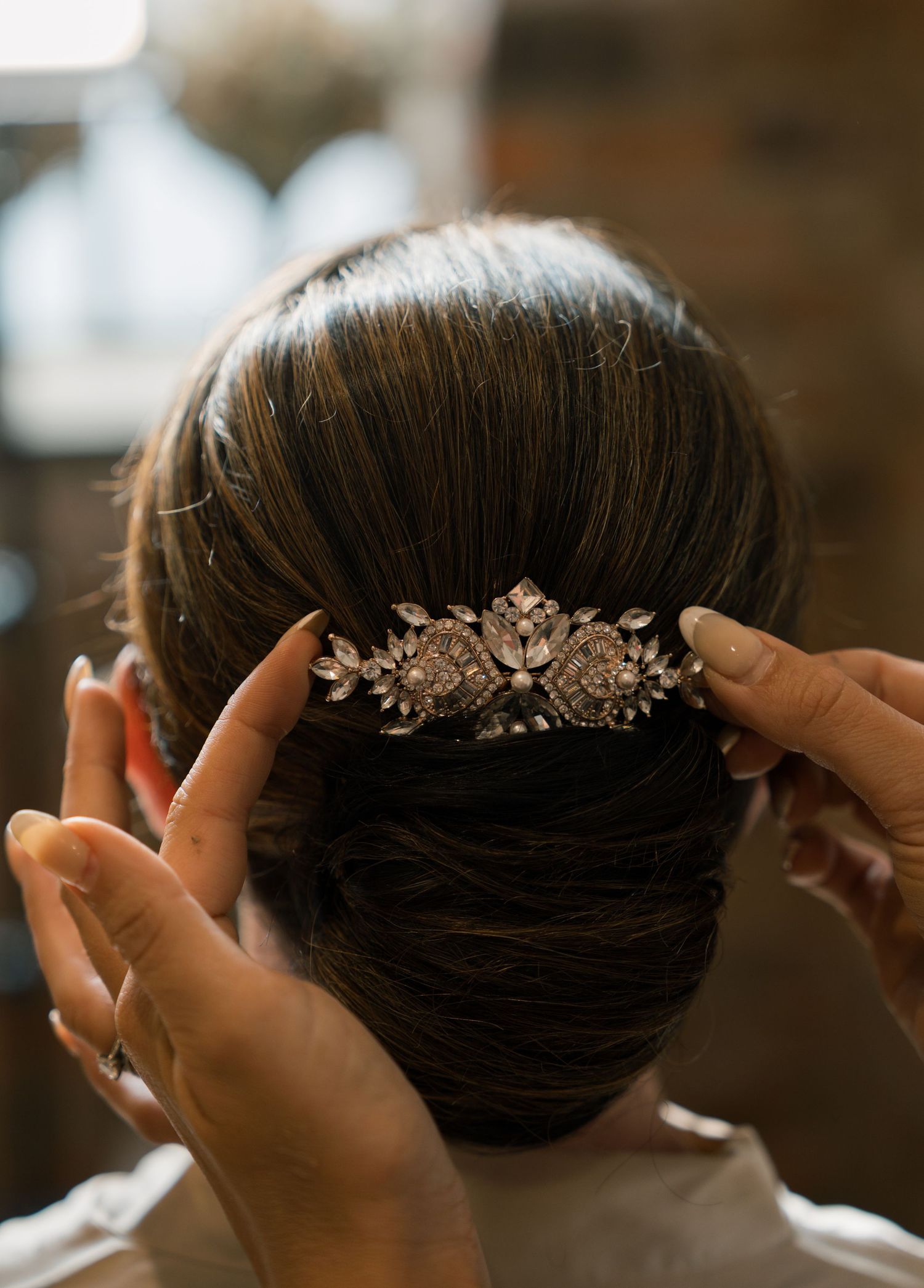 Ornate crystal bridal hair comb being placed in an elegant updo hairstyle.