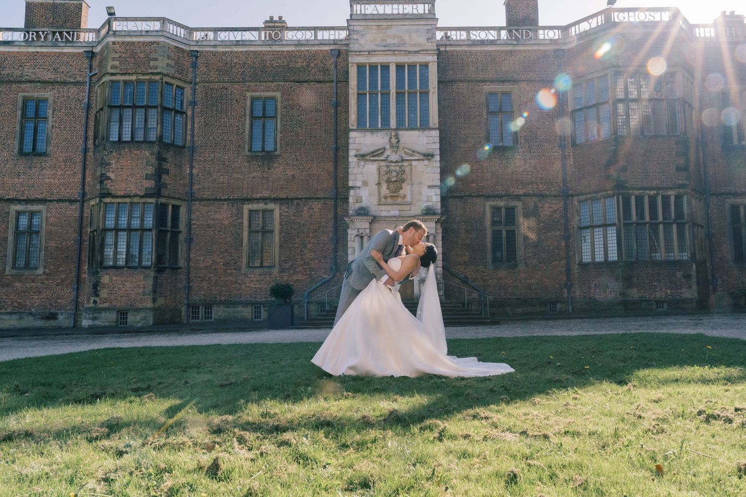 Wedding couple in front of historic stone building with beautiful sunlight.