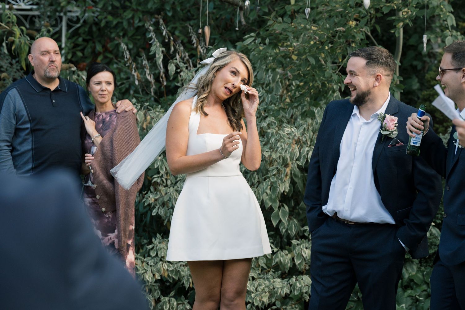 Wedding guests enjoying an outdoor celebration with string lights and greenery in the background.