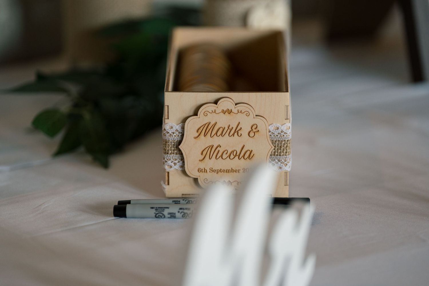 Elegant wooden place card holders with engraved names displayed on a white tablecloth at a wedding reception.