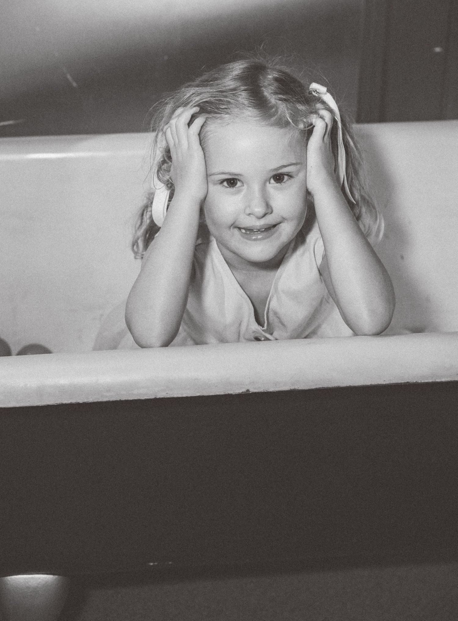 Black and white photo series shows playful expressions through a white window frame.