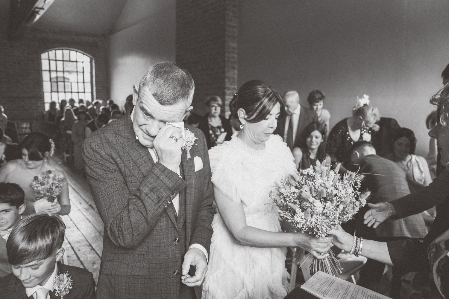 Black and white photo of wedding celebration with guests in industrial venue.