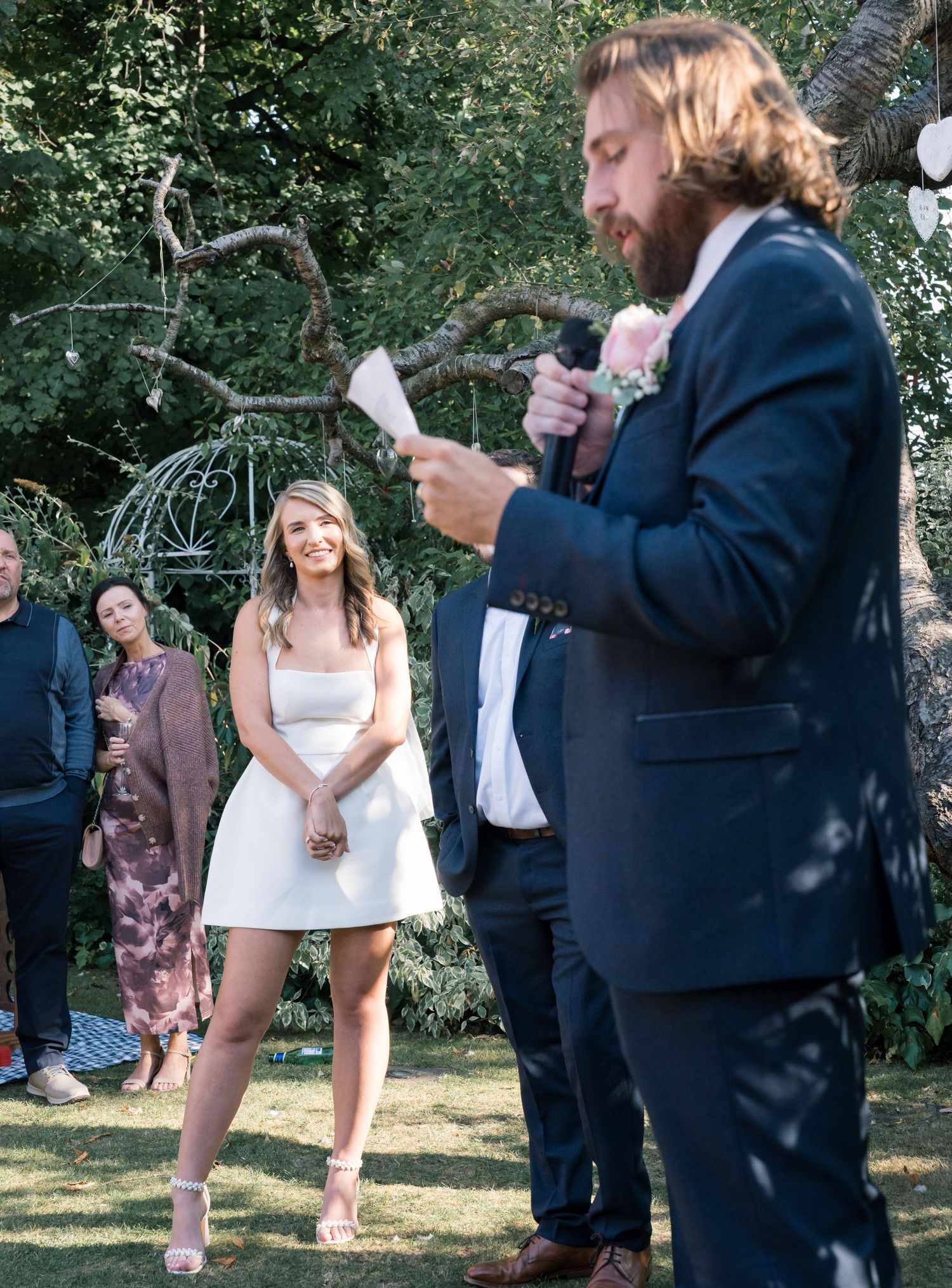 Wedding guests enjoying an outdoor celebration with casual dancing and laughter in a garden setting.