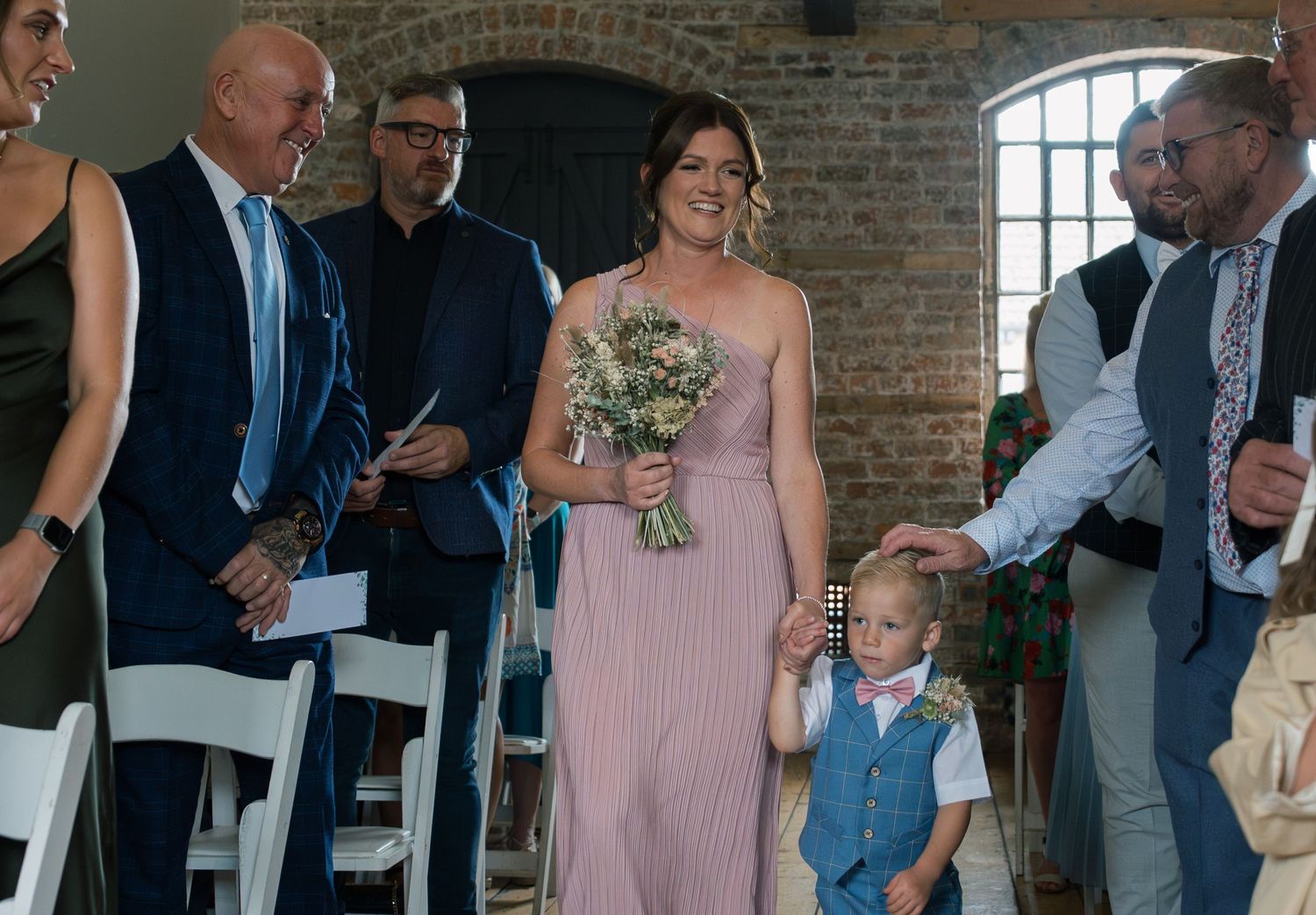 Wedding guests mingle and socialize during a reception in a rustic brick-walled venue.