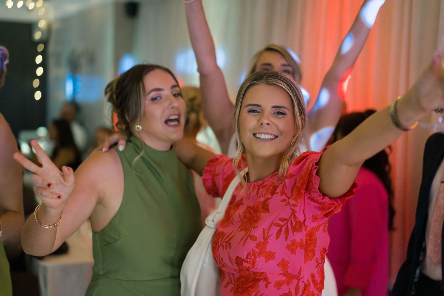 Wedding reception dance party with colorful lighting and energetic dancing.