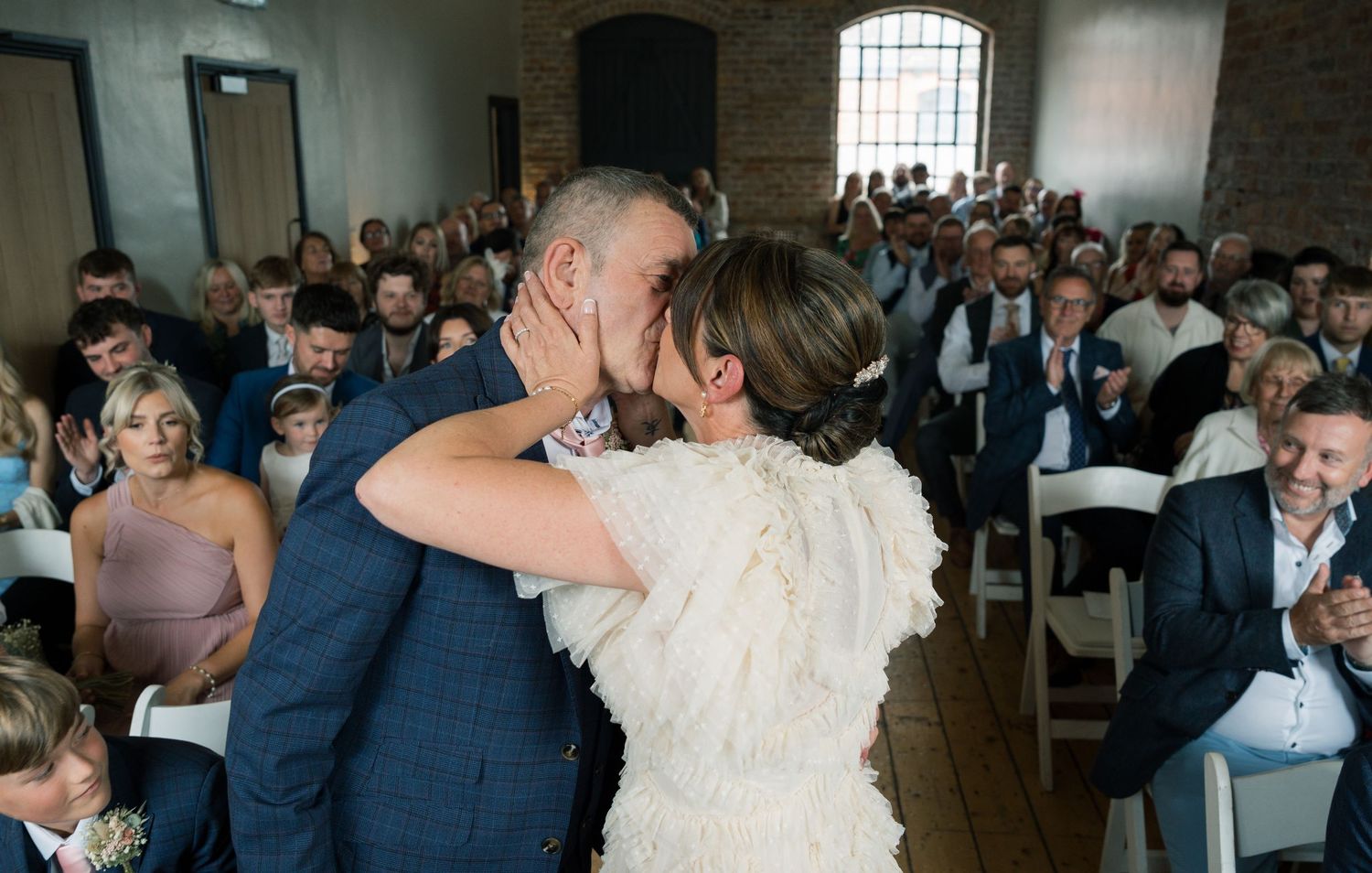 Wedding celebration candid shots showing guests dancing and celebrating in an industrial brick venue.