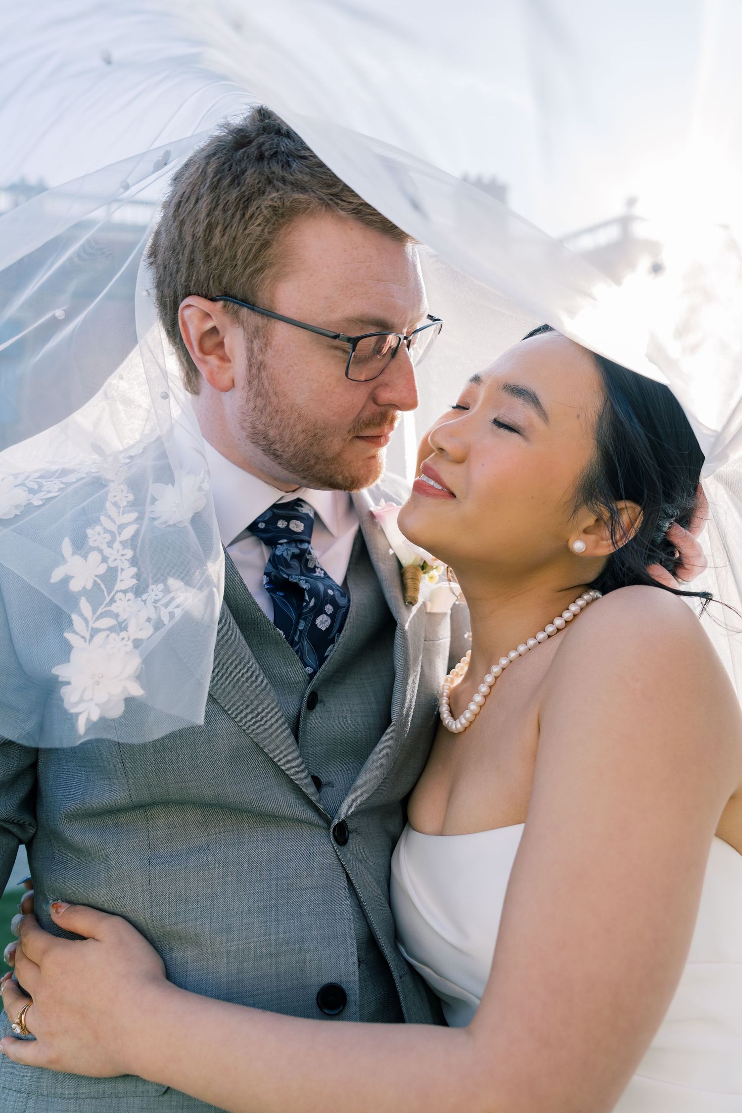 A romantic wedding couple embraces outdoors with snowy mountains in the background on their special day.