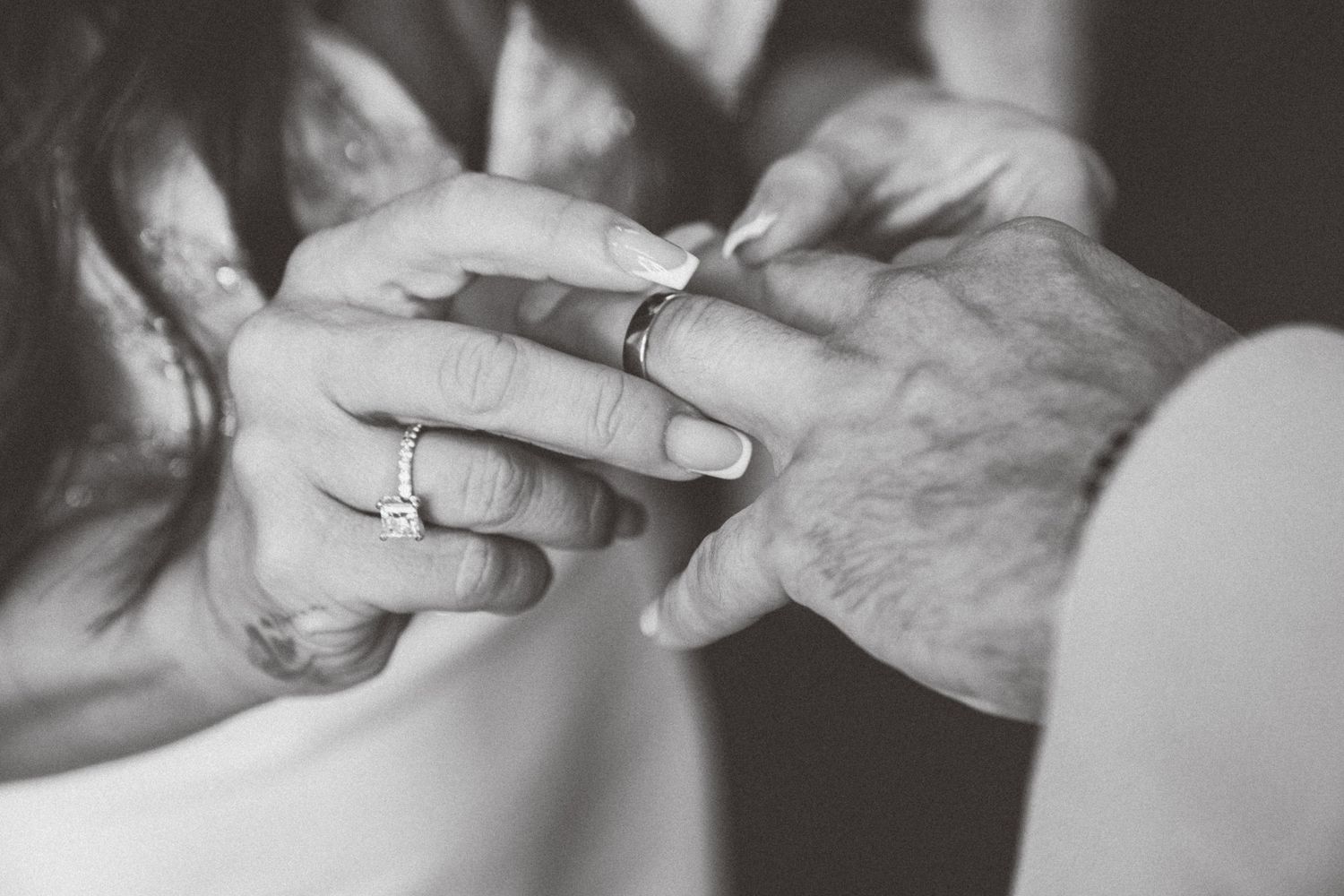 Black and white photo of hands exchanging wedding rings during a marriage ceremony.