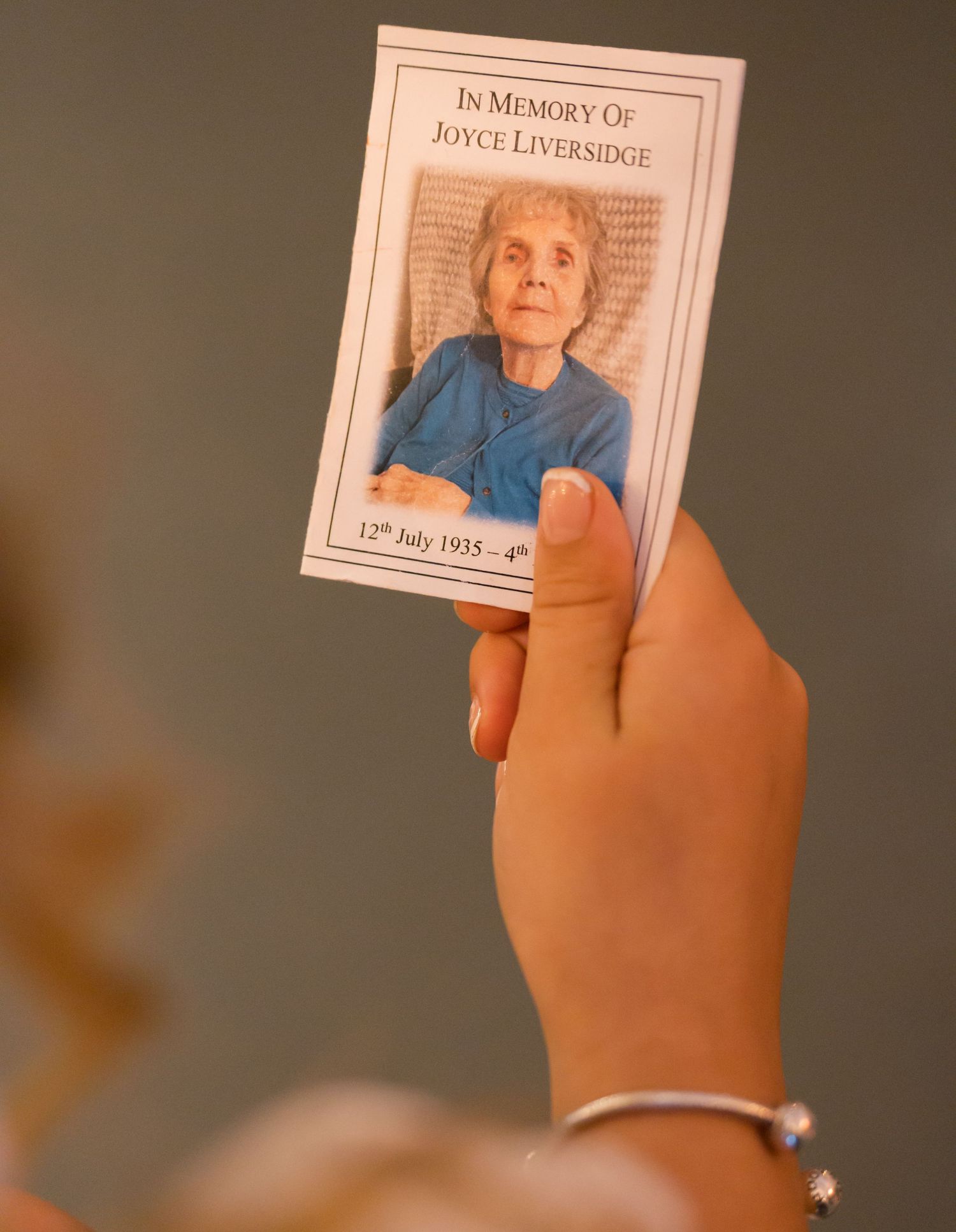 Hand holding a memorial photo frame against dark background.