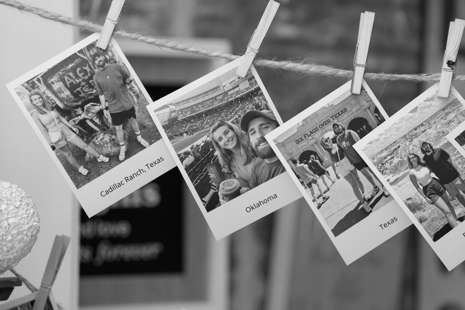 Row of vintage-style photographs hanging on string with clips against a light background.
