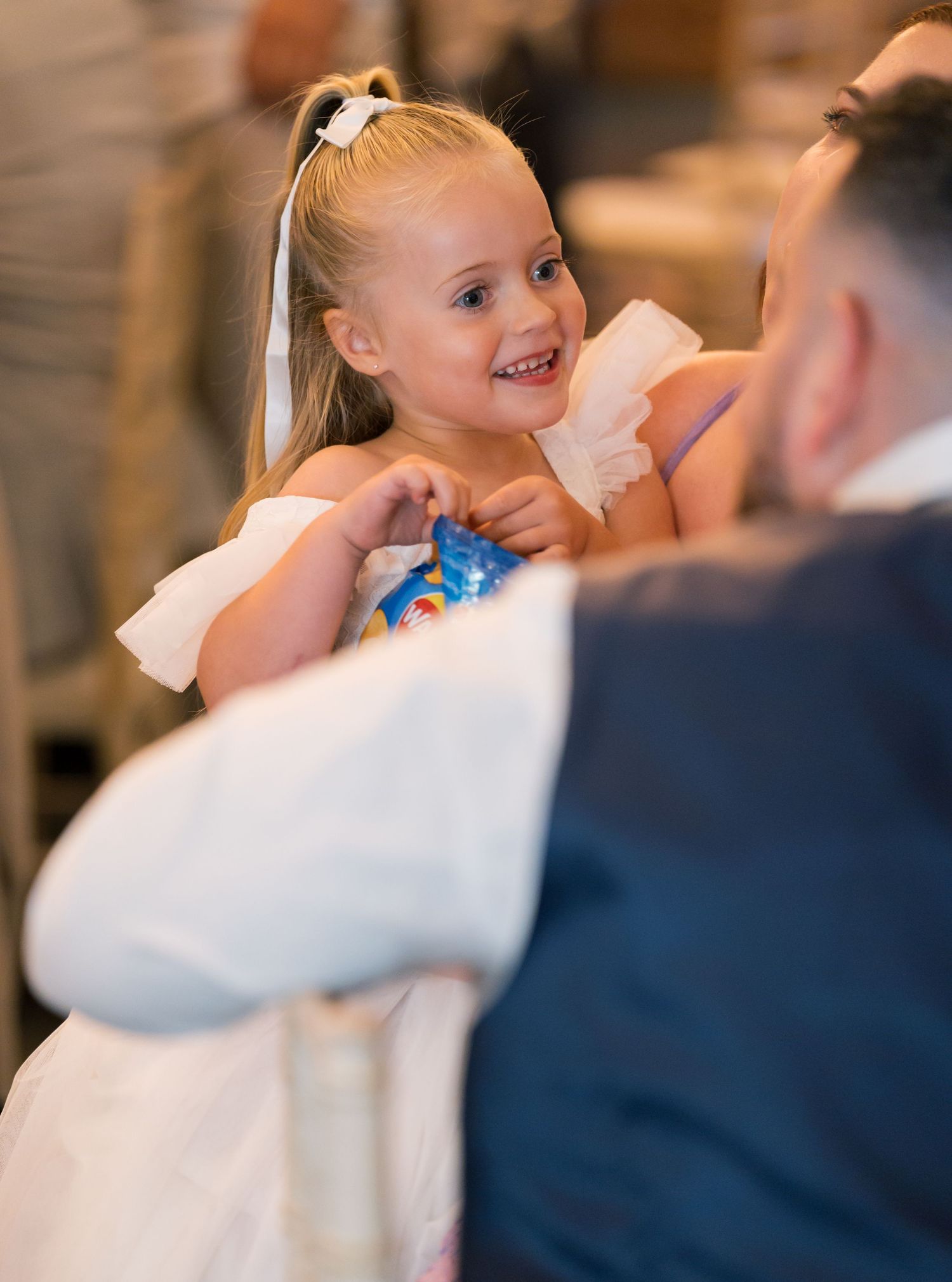 Young flower girl in white dress dances joyfully at wedding reception.