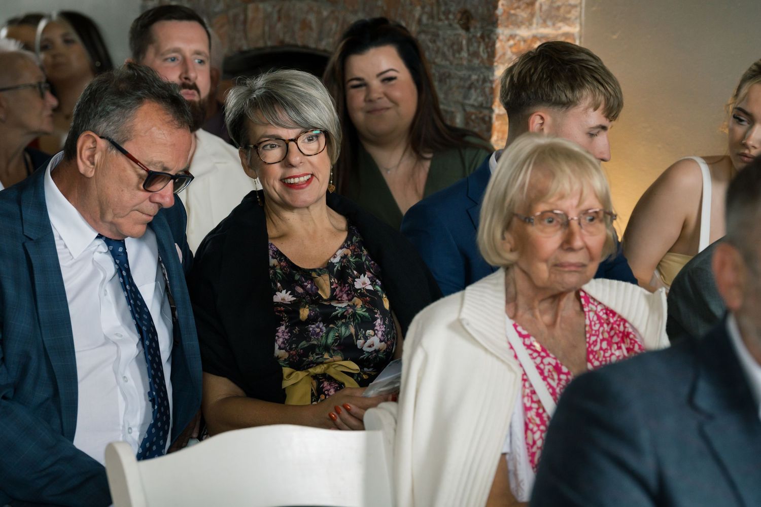 Wedding guests gathered together watching ceremony proceedings indoors.