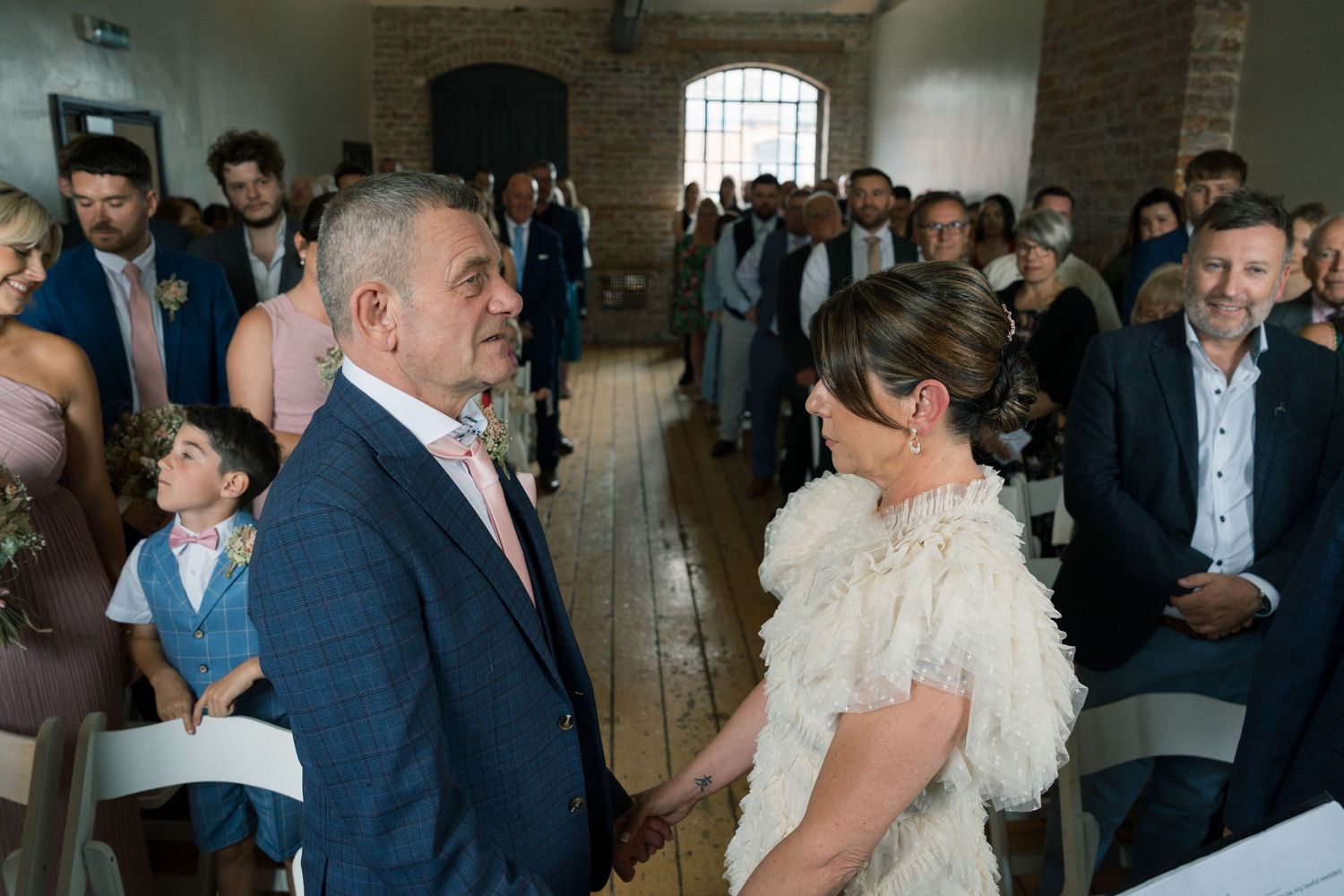 Wedding guests gather in a rustic brick-walled venue during a celebration.