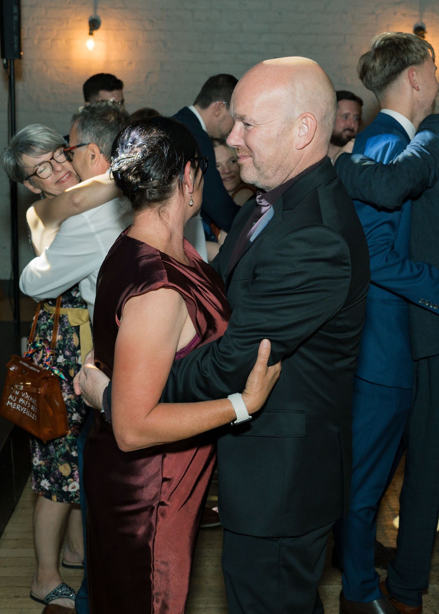 Wedding reception couples dance in dimly lit industrial venue.
