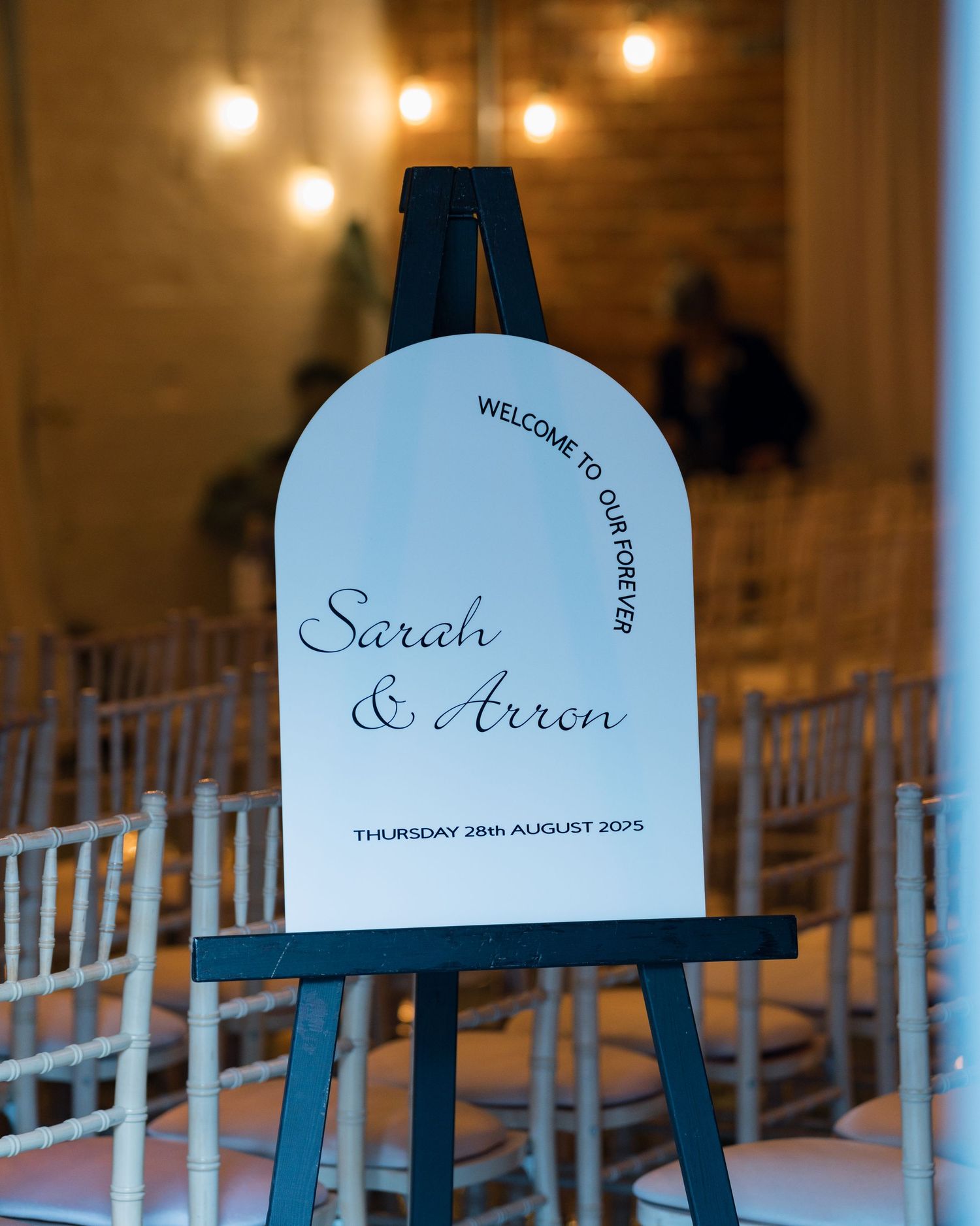 Welcome signs for Sarah and Aaron's wedding displayed on elegant black stands with warm lighting.