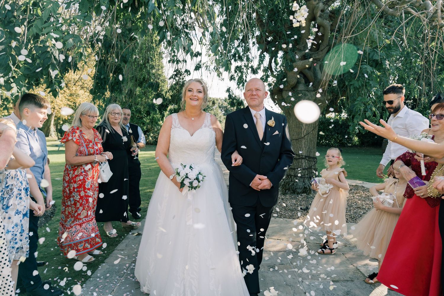 Guests throw confetti at the newlyweds during their outdoor garden celebration.