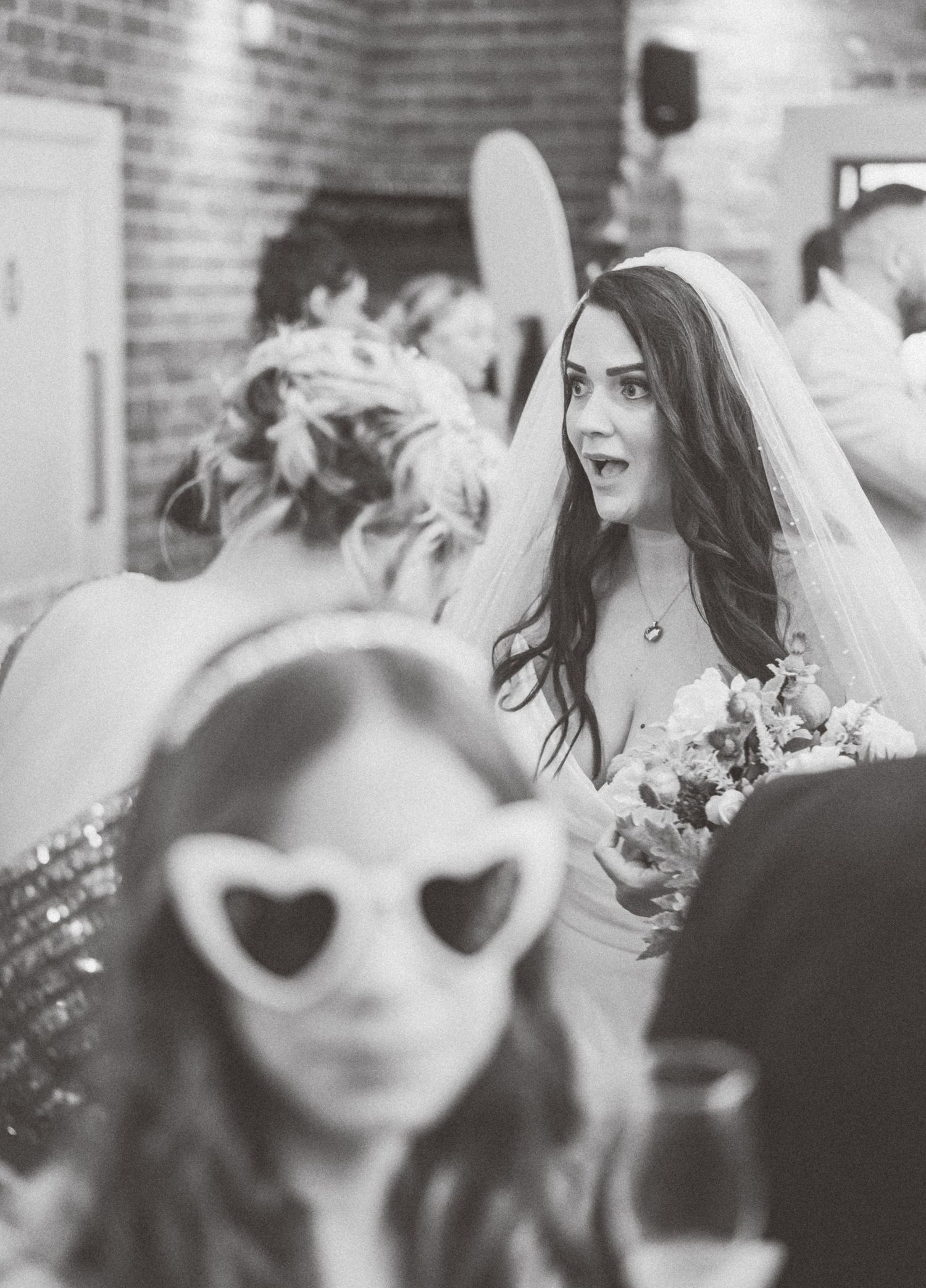 Black and white photo capturing candid reactions and emotions during a wedding ceremony.